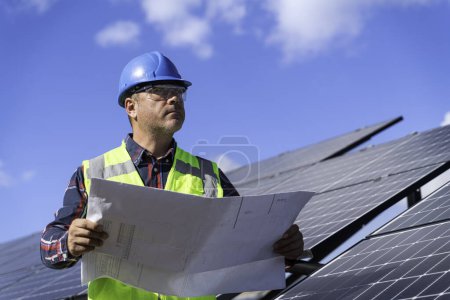 Foto de Retrato del ingeniero gerente masculino en la comprobación del casco de seguridad con el proyecto una operación del sistema del panel solar en la estación solar - Imagen libre de derechos