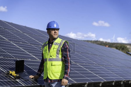 Foto de Hombre en uniforme y casco trabajando en paneles solares en la planta de energía solar. - Imagen libre de derechos