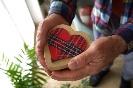 Foto de Heart-shaped gift box in the hands of an old pension man - Imagen libre de derechos