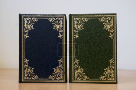 Blue and green cover of vintage books with frame of golden details and bound in leather on the shelf