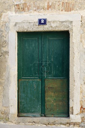 Foto de Casa número dos sobre la puerta de la ruina de una antigua casa de piedra con una puerta de madera - Imagen libre de derechos