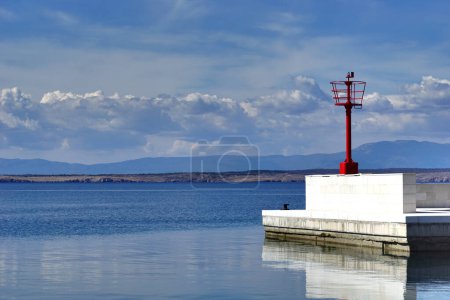 The red lighthouse at the entrance to the city harbor during a beautiful spring day