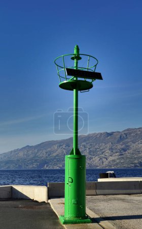Faro verde pequeño de metal simple en el puerto de la isla de Pag en Croacia