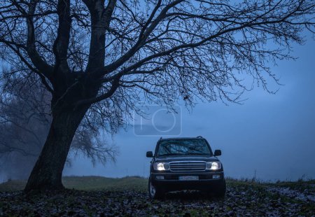 Téléchargez les photos : Foggy paysage riverain avec SUV sous la pluie - en image libre de droit