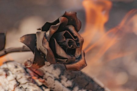 Metaphorical installation with a forged rose in fire and smoke