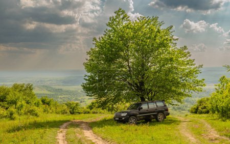SUV viaja a través del campo montañoso en primavera Cárpatos