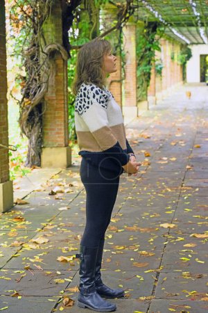 Photo for Capturing an attractive brunette in clothing that matches the autumnal colours of the temple, at Valley Gardens, Harrogate. - Royalty Free Image