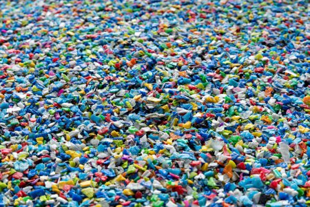 Petits morceaux de plastique broyé. Bouchons de bouteille broyés pour le recyclage. Déchets plastiques qui seront mélangés avec du vergin plastique. Concept réduisant le plastique.