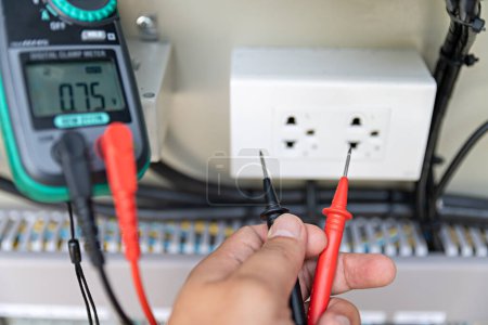 L'électricien utilise un pince-mètre dijital pour réparer l'équipement électrique. Concept énergétique. circuit électrique. Vérifiez la tension avant de commencer le travail. La sécurité d'abord.