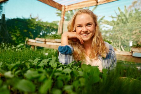 Téléchargez les photos : Happy young caucasian woman in checked shirt looking at camera with hand on chin by plants in plant nursery - en image libre de droit