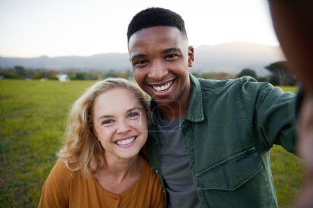 Téléchargez les photos : Happy young multiracial couple in casual clothing smiling and looking at camera in field - en image libre de droit