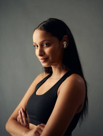 Téléchargez les photos : Portrait of biracial young woman wearing sports bra looking at camera with wireless in-ear headphones - en image libre de droit
