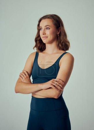 Téléchargez les photos : Jeune femme caucasienne portant des vêtements de sport regardant loin avec les bras croisés en studio - en image libre de droit