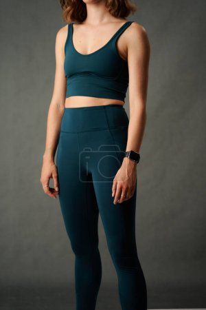 Photo for Midsection of athletic young caucasian woman wearing sports clothing and fitness tracker in studio - Royalty Free Image