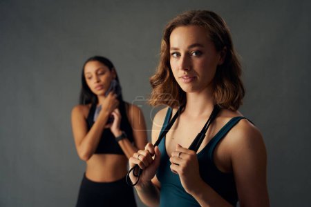Téléchargez les photos : Confident young women wearing sportswear holding jump rope over shoulder while taking a break - en image libre de droit