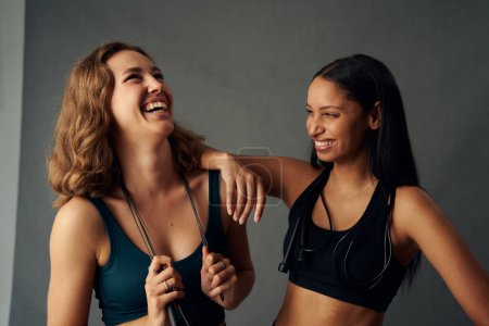 Foto de Mujer joven con ropa deportiva sosteniendo la cuerda de salto mientras se ríe con un amigo - Imagen libre de derechos