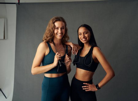 Téléchargez les photos : Jeunes femmes portant des vêtements de sport souriant tout en tenant des cordes de saut et en regardant la caméra - en image libre de droit