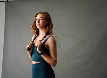 Téléchargez les photos : Focused young caucasian woman in sportswear holding skipping rope over shoulders in studio - en image libre de droit