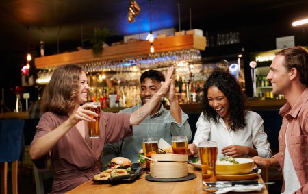 Foto de Joven grupo multirracial de amigos con ropa casual celebrando con comida y bebidas en el restaurante - Imagen libre de derechos