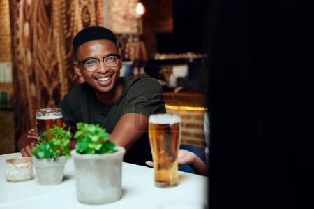 Téléchargez les photos : Heureux jeunes amis multiraciaux portant des vêtements décontractés souriant et gesticulant avec des boissons au restaurant - en image libre de droit