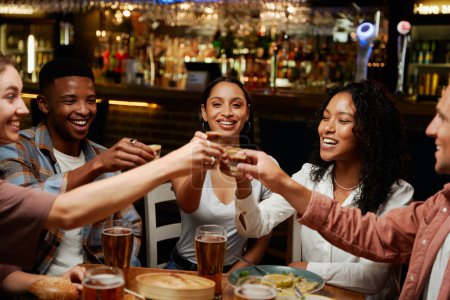 Foto de Joven grupo multirracial de amigos con ropa casual disfrutando de la cena en el restaurante - Imagen libre de derechos