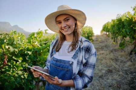 Foto de Feliz joven caucásico mujeres con ropa casual sosteniendo tableta digital al lado de las plantas en la granja - Imagen libre de derechos