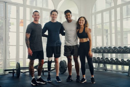 Téléchargez les photos : Portrait de groupe de jeunes adultes multiraciaux heureux portant des vêtements de sport regardant la caméra à la salle de gym - en image libre de droit