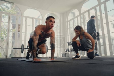 Téléchargez les photos : Quatre jeunes adultes en forme portant des vêtements de sport faisant des exercices à la salle de gym - en image libre de droit