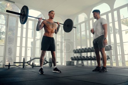 Photo for Two athletic multiracial young men wearing sports clothing doing weightlifting at the gym - Royalty Free Image