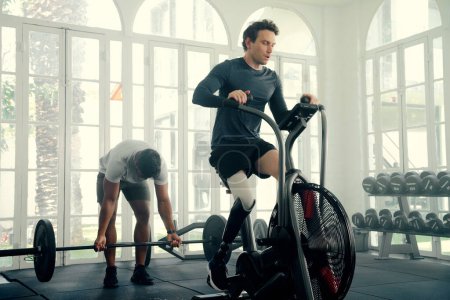 Photo for Two multiracial young men wearing sports clothing exercising with fitness equipment at the gym - Royalty Free Image