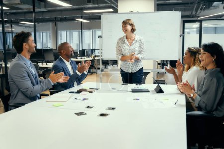 Photo for Group of happy multiracial business people applauding around conference table in corporate office - Royalty Free Image