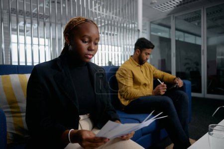 Foto de Dos jóvenes empresarios multirraciales con papeles de lectura de ropa de negocios y tableta digital en la oficina - Imagen libre de derechos