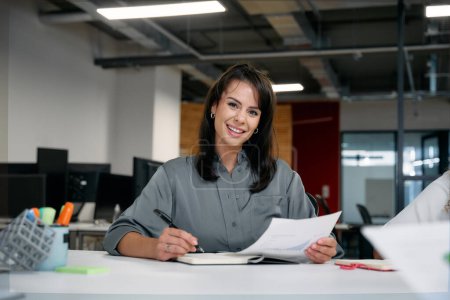Téléchargez les photos : Deux femmes d'affaires multiraciales heureuses souriantes tout en examinant les documents lors d'une réunion au bureau de l'entreprise - en image libre de droit