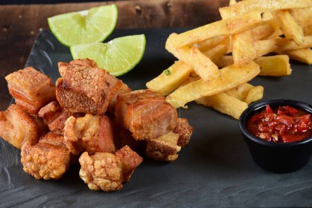 Photo for Fried pork skin crackling pork pancetta pururuca typical brazilian food with lemon and french fries - Royalty Free Image