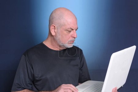 Photo for Adult man using notebook handheld computer use of communication technology and service "S3niorLife". - Royalty Free Image