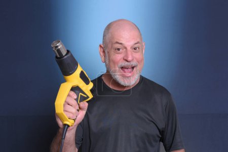 Photo for Adult man using holding heat gun service equipment tool for heating materials"Senior Life" - Royalty Free Image