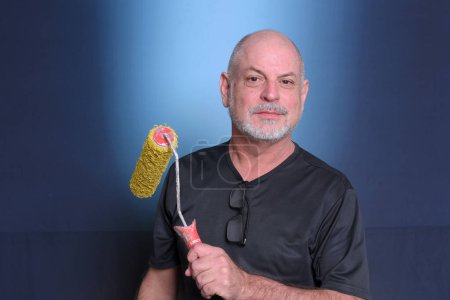 Photo for Adult man using holding paint roller brush paint service equipment painting and texture material objects"Senior Life". - Royalty Free Image