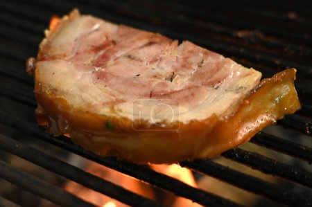 Photo for Bacon pork rinds roasting on a charcoal barbecue lit wood with fire for roasting pork pancetta on the grill taste - Royalty Free Image