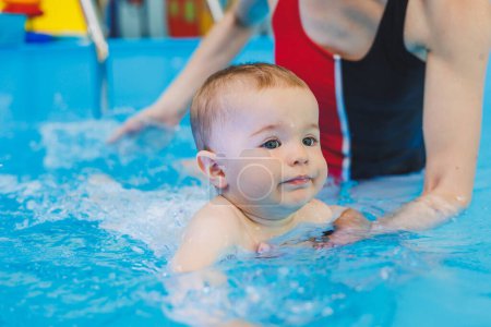 Photo for A swimming teacher teaches a little boy to swim in the pool. Children's first swimming lessons. Development for babies - Royalty Free Image