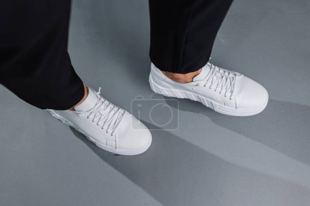 Photo for Close up of male legs in black pants and white casual sneakers. Men's leather summer shoes - Royalty Free Image