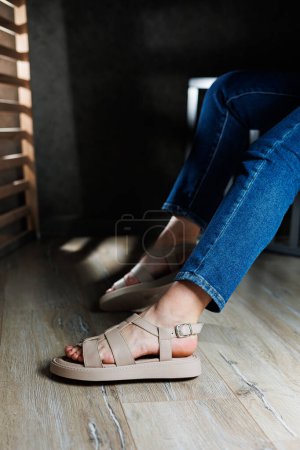 Téléchargez les photos : Sandales d'été pour femmes. Collection de sandales d'été en cuir pour femme. Jambes féminines fines en sandales en cuir beige sans talons. - en image libre de droit