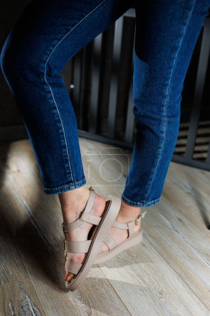 Téléchargez les photos : Sandales d'été pour femmes. Collection de sandales d'été en cuir pour femme. Jambes féminines fines en sandales en cuir beige sans talons. - en image libre de droit