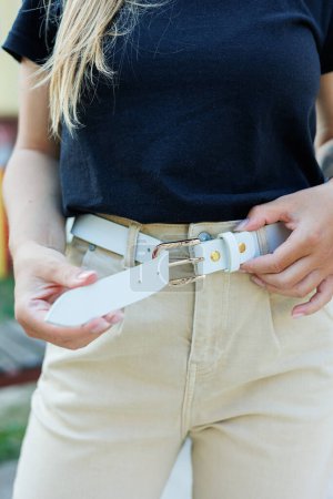 Women's white leather belt for trousers. A white belt on a woman's waist