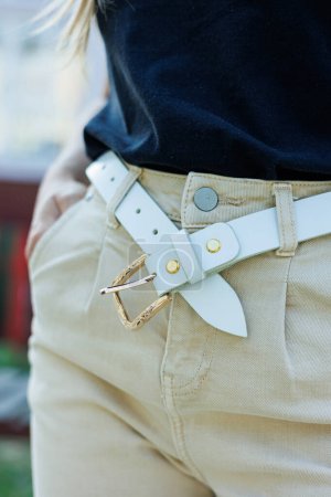 Women's white leather belt for trousers. A white belt on a woman's waist