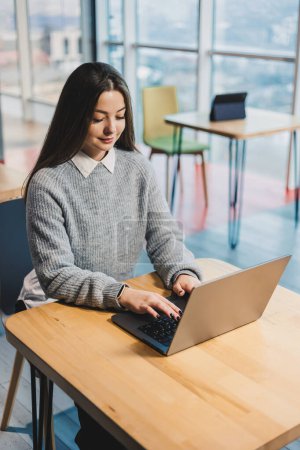 Femme d'affaires mignonne assise à un bureau dans un espace de travail moderne travaillant sur un ordinateur portable. Processus de travail d'une femme au bureau