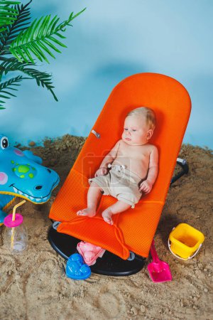 Photo for A baby is lying on a recliner chair for babies. Children's recreation. - Royalty Free Image
