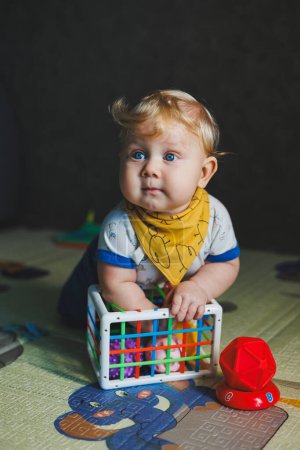 The child is lying on the mat, playing with soft balls. Educational toys for the motor skills of the baby's hands. Child development. Sensory experience