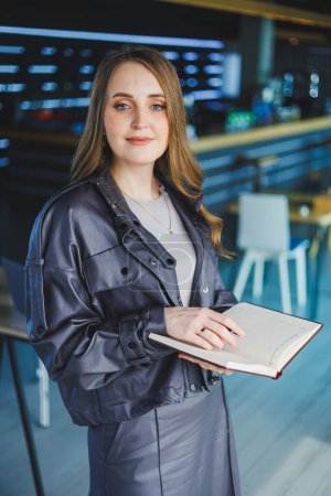 Una joven en la oficina toma notas en un cuaderno. Una mujer de negocios trabaja en un espacio de trabajo moderno