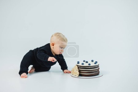 a little boy of 8 months on a white background lies near a cake. sweet cake for a little boy.
