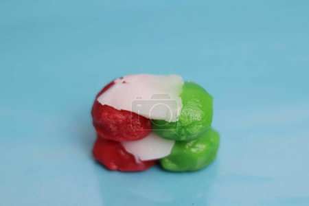 Foto de Snacks de mercado rojos y verdes llenos de coco rallado dulce. bocadillos de mercado sobre un fondo azul - Imagen libre de derechos